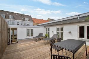 a patio with a table and chairs on a wooden deck at Central 3-bedroom apartment with a big terrace and fitness room in Aalborg