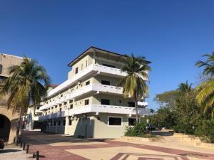 a white building with palm trees in front of it at Condominio Alegre Amanecer in Santa Cruz Huatulco