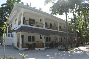 a large white building with a balcony and trees at Evolution Dive and Beach Resort in Malapascua Island