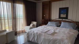 a bedroom with a large white bed and a chair at Sunshine Gypsy at Beach Villa Vibhavadi Pattaya in Na Jomtien