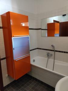 uma casa de banho com um armário laranja e uma banheira em qu4ttro em Riva del Garda