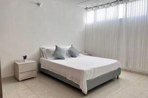 a white bedroom with a bed and a window at Apartamento en Cali - Cuarto de Legua in Cali