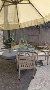 a table with an umbrella and two chairs under it at gite du pré in Gorron