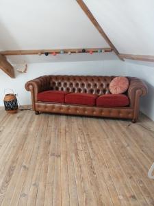 a brown couch sitting in a room with a wooden floor at gite du pré in Gorron