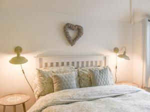 a bedroom with a bed with a heart sign on the wall at Wisteria Cottage in New Milton