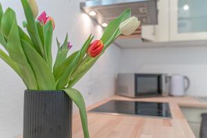a black vase with flowers in it on a kitchen counter at Apartment Wesseling in Wesseling
