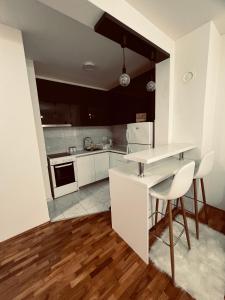 a kitchen with white cabinets and a table and chairs at Apartman Lux in Vranje