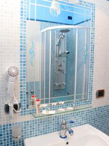 Baño de azulejos azules con lavabo y espejo en B&B Il Pavone en Conca dei Marini