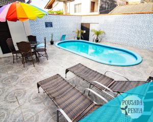 una piscina con sillas, una mesa y una sombrilla en Pousada Penha 1 Beto Carrero, en Penha