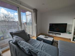 a living room with a couch and a large window at Luxury One Bedroom Flat in Deptford in London