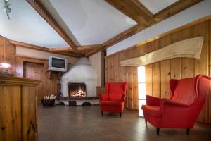 a living room with two red chairs and a fireplace at T3 Gasthof Spullersee in Wald am Arlberg