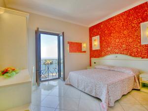 ein Schlafzimmer mit einem Bett und einer roten Wand in der Unterkunft B&B Il Pavone in Conca dei Marini