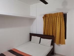 a bed in a room with a yellow curtain at Nallur Holidays Inn in Jaffna