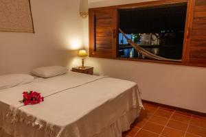 a bedroom with a white bed with a flower on it at Vila Tao in Fortim