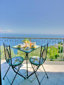 een tafel en stoelen op een balkon met uitzicht op de oceaan bij B&B Il Pavone in Conca dei Marini