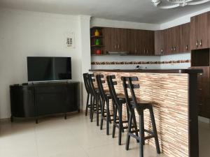 una cucina con bar con sedie e televisore di Kiosco Azul - Apartamento amoblado cerca al mar a Ríohacha
