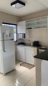 uma cozinha com armários brancos e um frigorífico branco em Privê estrela em Porto de Galinhas
