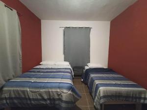 two beds in a room with red and white walls at Amplio y familiar in Cabo San Lucas