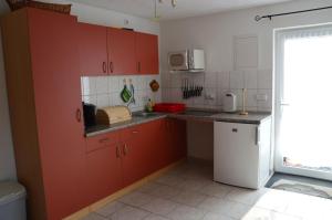 a kitchen with red cabinets and a white refrigerator at Ferienhaus Abendsonne in Born
