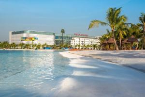 a view of a beach with a hotel and palm trees at Titmit Studio-Căn hộ cao cấp VinhomesOceanPark in Hanoi