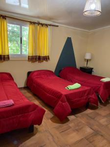 three beds in a room with red sheets at PHouse in Las Heras