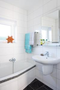 a white bathroom with a sink and a bath tub at FH Ostfriesland to Huus, zw. Emden und Greetsiel in Hinte