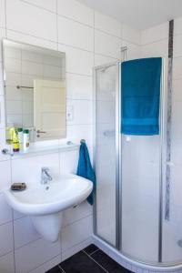 ein weißes Bad mit einem Waschbecken und einer Dusche in der Unterkunft FH Ostfriesland to Huus, zw. Emden und Greetsiel in Hinte