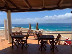 eine Terrasse mit Tischen und Sonnenschirmen und dem Meer in der Unterkunft Cosy & Relax Yellow House 5mn walk from the beach! in Calheta Do Maio