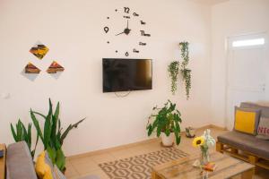 a living room with a couch and a clock on the wall at Cosy & Relax Yellow House 5mn walk from the beach! in Calheta Do Maio