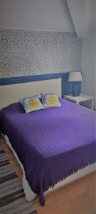 uma cama roxa com duas almofadas num quarto em Santo António's Guesthouse em Cascais