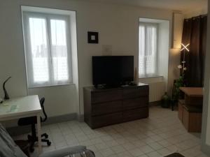 ein Wohnzimmer mit einem TV auf einer Kommode mit Fenstern in der Unterkunft Pégase meublé 3*** in Fourchambault