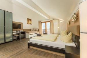 um quarto com uma cama, uma secretária e uma televisão em T3 Gasthof Spullersee em Wald am Arlberg