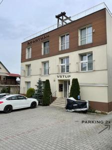 une voiture blanche garée devant un bâtiment dans l'établissement Apartmán Dominika Bojnice, à Bojnice