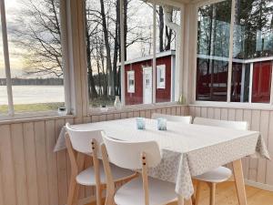 una mesa blanca y sillas en una habitación con ventanas en Holiday home GRIMSTORP en Grimstorp