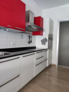 uma cozinha branca com armários vermelhos e um lavatório em qu4ttro em Riva del Garda