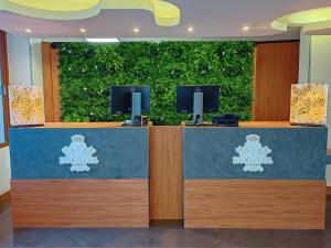 a reception desk with a green hedge at Luxotel Cannes in Cannes