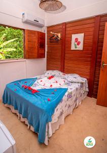 um quarto com uma cama com um cobertor azul em Campos Elísios Boipeba na Ilha de Boipeba