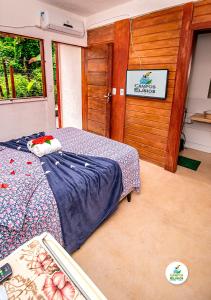 um quarto com uma cama e uma parede de madeira em Campos Elísios Boipeba na Ilha de Boipeba