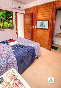 een slaapkamer met een bed en een houten wand bij Campos Elísios Boipeba in Ilha de Boipeba