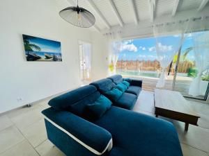 un soggiorno con divano blu e una grande finestra di Villa Amaryllis luxueuse,piscine,vue mer,plage a Sainte-Luce