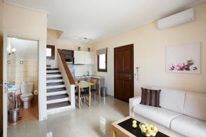 a living room with a white couch and a kitchen at Aithra -Agios Petros Andros in Gavrio