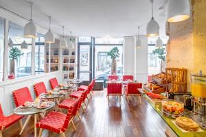 un restaurant avec des chaises rouges, des tables et des fenêtres dans l'établissement Hotel Monterosa - Astotel, à Paris