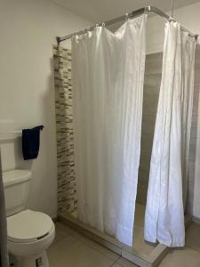 ein Bad mit einem WC und einem Duschvorhang in der Unterkunft Casa Zona Iteso, Expo, Plaza del Sol, 4 habitaciones 8 huespedes / compartida in Guadalajara