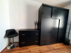 un armario negro y una silla en una habitación en Apartman Dukat Vukovar en Vukovar