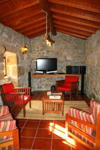 sala de estar con muebles de color rojo y TV en Casa Da Rocha, en Caldelas