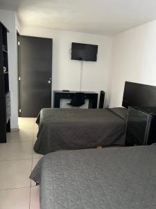 a hotel room with two beds and a flat screen tv at Casa Zona Iteso, Expo, Plaza del Sol, 4 habitaciones 8 huespedes / compartida in Guadalajara