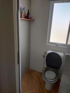 a small bathroom with a toilet with a window at Bj Chalets - De Rug 3 - Vakantiepark Lauwersoog - Luxe kindvriendelijke chalet MET vaatwasser en inloopkast! Vroege incheck! in Lauwersoog