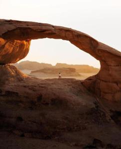 a person standing in an arch in the desert at WADI RUM-Bedouin Tents and Jeep Tours in Wadi Rum