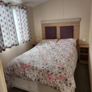 a bedroom with a large bed with a floral bedspread at 4 BEDROOMS CARAVAN at Waterside Leisure Holiday Park in Skegness