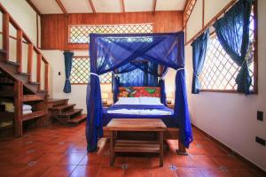 a bedroom with a bed with a mosquito net at Hotel Casa Merlin in Puerto Viejo